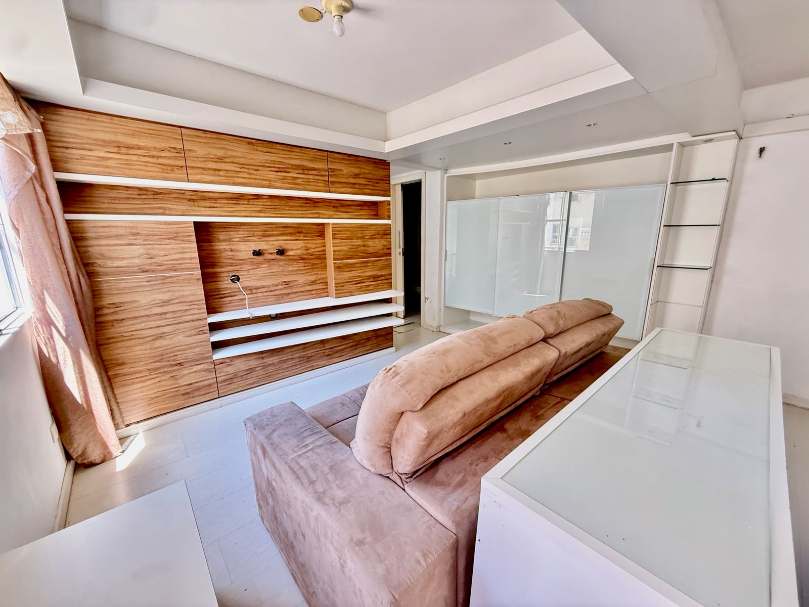 Sala integrada do apartamento com painel em madeira e sofá